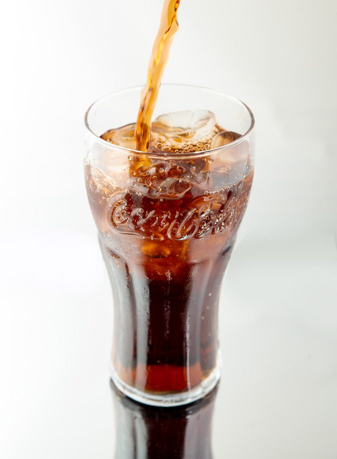 Pack shot of coca-cola being poured into a glass